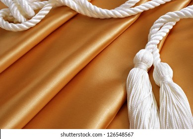 Textile Background Image Of Gold Satin Fabric With Drapery Cords (or Graduation Honor Cords)