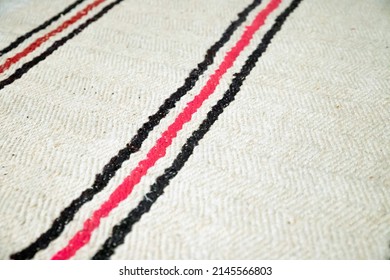 Textile cotton white rug with black and red stripes. Texture background. Close-up floor carpet
