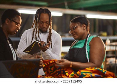 Textile industry employer and employees looking at laptop having a production meeting - Powered by Shutterstock