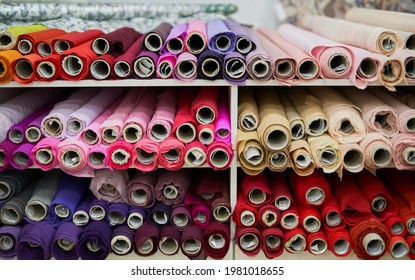 Textile retail store, drapery or drapery shop. Close-up colorful linen fabric rolls in pink, orange, beige, purple colors. E-commerce, offline sale, tailor or atelier concept. High quality image