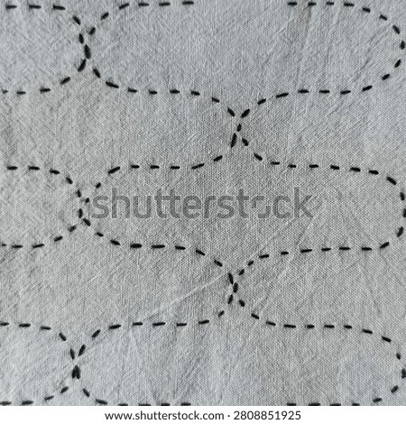 Textile Sampler with Traditional Japanese Pattern. Collection of handmade sashiko embroidery samplers on blue, gray and pink fabric. Traditional Japanese geometric stitch patterns photographed on a light background. Textile art samples for embroidery inspiration, craft, design and educational use.
