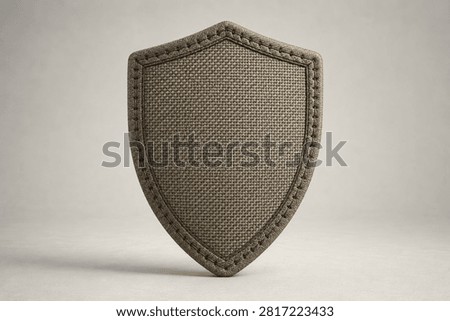 Textile shield, canvas material. Stitched border, subtle texture. Simple, protective, defensive.