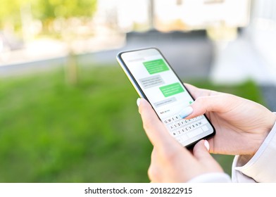 Texting sms with phone in city outdoor park. Woman sending text message with cellphone. Chatting on instant messaging app. Person using smartphone. Conversation and discussion with friend online. - Shutterstock ID 2018222915