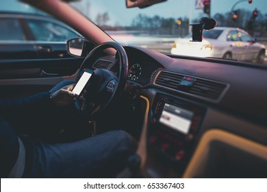 Texting While Driving Concept. Browsing Internet and Social Media While Behind the Wheel. Caucasian Men Texting During Car Drive.