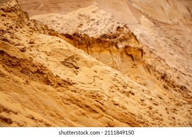 Textural sand, with a relief surface, multi-colored layers and different in size of granules, in an outdoor sand career, after mining ore and sand for construction. 