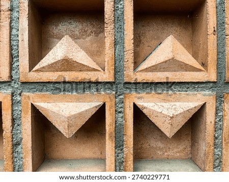 Texture of aged red brick wall, featuring geometric triangle shape decors. The pattern creates a unique shaped textured background. Useful for construction, exterior, design, housing, or arts related.