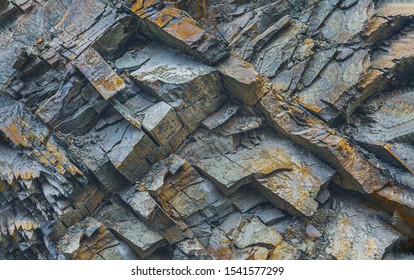 Texture or background layers and cracks in sedimentary rock on cliff fake, selective focus. Cliff of rock mountain, soft focus. Rock slate in the mountain. Cracks of sandstone.