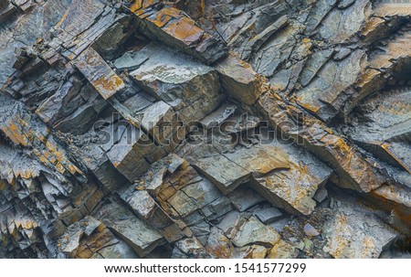 Texture or background layers and cracks in sedimentary rock on cliff fake, selective focus. Cliff of rock mountain, soft focus. Rock slate in the mountain. Cracks of sandstone.