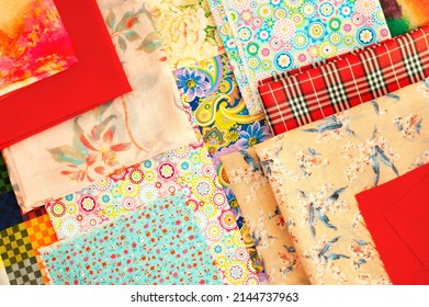 Texture background from layers of folded fabric. Multi-colored fabric for sewing clothes. Lots of colorful textiles.
