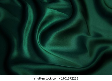 Текстура, фон, узор. Текстура зеленой шелковой ткани. Красивая изумрудно-зеленая мягкая шелковая ткань.