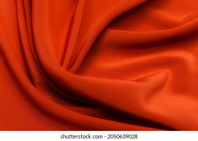 Texture, background, pattern. Texture of red or orange silk or cotton or wool fabric. Beautiful pattern of fabric.