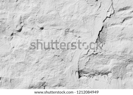 Texture background, pattern. The wall is lined with granite stones and whitewashed with lime. a continuous vertical brick or stone structure that encloses or divides an area of land.