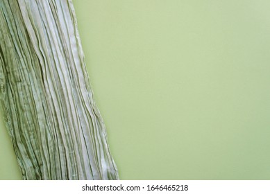 The texture of the background picture the olive and sage green corrugated fabric with parallel or diagonal folds on textured paper. Blank for design, concept of nature, springtime, fresh greenery.