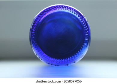 Texture background: round bottom of a glass dark blue transparent bottle on a gray background, cobalt circle, disk