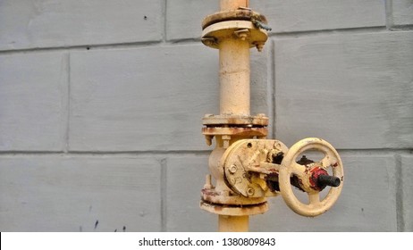 Texture, background, wallpaper, image of an old yellow idle or non-working crane or fire hydrant on a pipe near a residential or public building in spring or autumn.