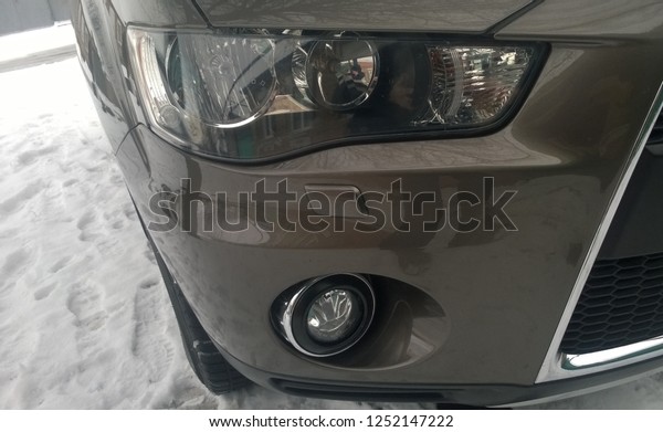 Texture or backgroung\
of the front right side and headlight of the modern brown car with\
the right lower fog light on a clear winter day. Japanese expensive\
car crossover.