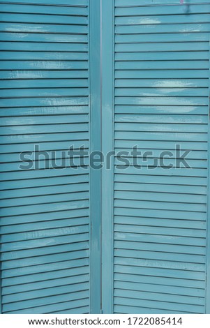 The texture of the battens of a blue wooden slats screen. Casement shutters close-up. Wooden louvre. Louvred grille made of wood