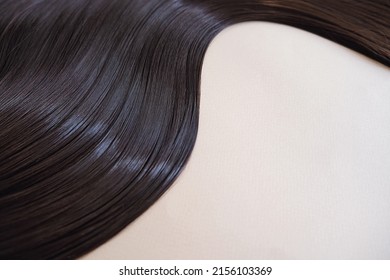 texture of beautiful glossy long hair.Curl female healthy hair. Concept hairdresser spa salon. strand of brunette silky hair.