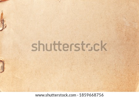 Texture of beige old paper with rust clip, crumpled background. Vintage brown grunge surface backdrop. Craft notebook with staple.