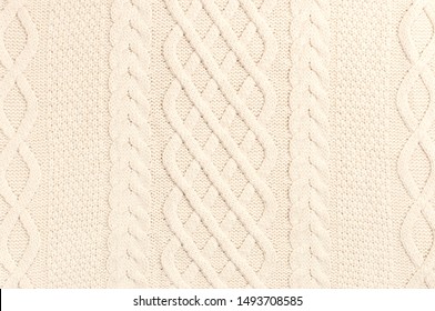 The texture of beige sweater pullover. Knitted background. Knitted texture. A sample of knitting from wool. Handmade sweater texture, knitted wool pattern