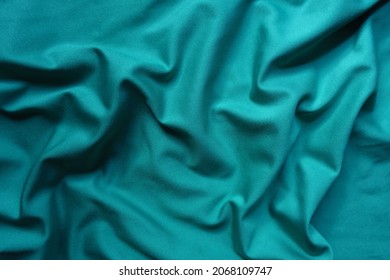 Texture of blue green polyester fabric in soft folds