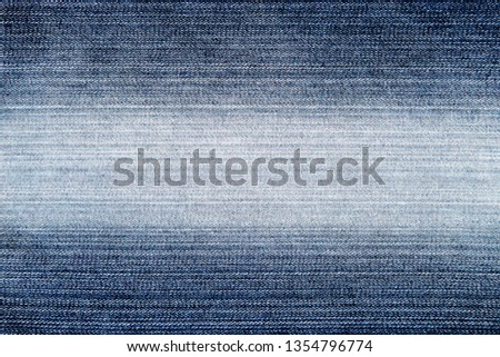 The texture of blue jeans with a light white stripe in the middle of the denim fabric for the background.