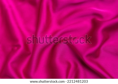 Texture of bright pink tissue silk or satin. Fabric fuchsia or crimson-colored color. Abstract background.