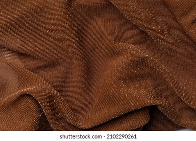 Texture of brown shiny fabric, textile background, drapery and pleats on delicate fabric. Macrophotography. Close-up of rippled white silk fabric. Top view. Flat lay. Crumpled fabric background