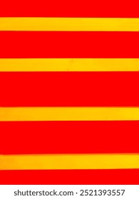 The texture of building wall with a yellow and red horizontal straight-line pattern.
