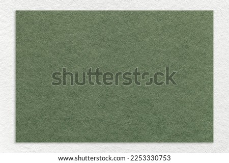 Texture of craft green color paper background with white border, macro. Structure of vintage dense kraft olive cardboard with empty frame. Backdrop with copy space.