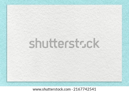 Texture of craft white color paper background with light blue border, macro. Structure of vintage dense kraft cardboard with turquoise empty frame. Backdrop with copy space.