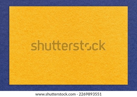 Texture of craft yellow color paper background with navy blue border, macro. Structure of vintage dense kraft golden cardboard with empty frame. Backdrop with copy space.