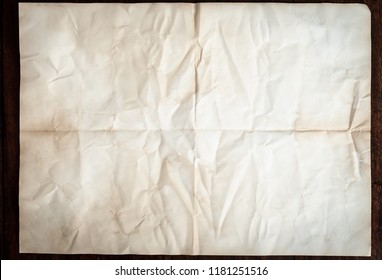 Texture Of Crumpled Folded Vintage Paper Background With Spot And Stain On Wooden Table