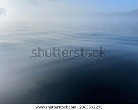 Texture of deep blue. Closeup of lake in Quebec, Saint-Donat called Lake Ouareau on a foggy morning with sun starting to set for the day. Calm water texture.  