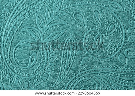 Texture of genuine leather with embossed floral trend pattern close-up, green mint color, for wallpaper or banner design. Fashionable modern background