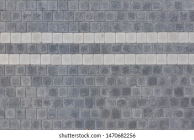 Texture of gray pavers with two white stripes. Сoncrete pavement cover - bicoloured stone blocks

