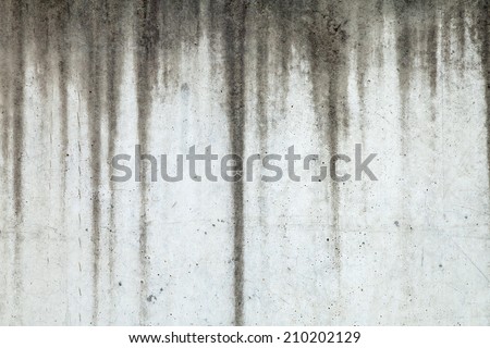 Texture of grey concrete wall with dark water marks running vertically down and many marks and lines