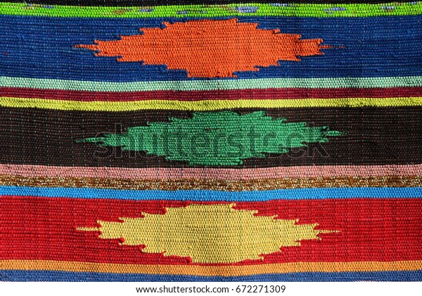 Texture of handmade\
carpet made on hand-loom with three colorful diamond shapes divided\
by vertical lines