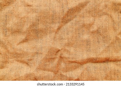Texture of jute canvas fabric as background, top view of crumpled creased material