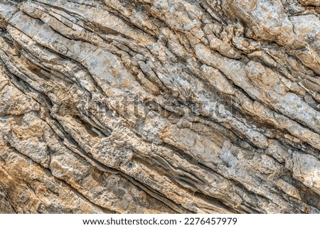 Texture of layered mineral formations on a rock in Budva, Montenegro. Geometric abstract diagonal lines in nature. Light beige-yellow pattern 