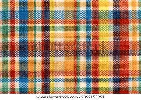 The texture of linen fabric in a large cage of blue, red, yellow and white. Scottish tailoring material. Checkered fabric