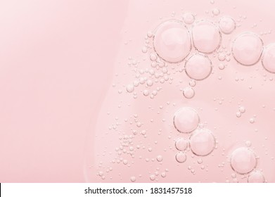 The Texture Of A Liquid Transparent Gel For Face Cleansing. Sample Of Oil Serum With Bubbles On A Pink Background. Moisturizing Cosmetic Beauty Product For Skincare. Lotion For Dry Skin Care