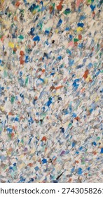 Texture made from recycled plastic, specifically from fused and pressed plastic waste granules, which is an eco-friendly approach to plastic waste disposal.