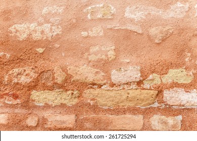 Texture of a medieval brick wall. Warm sienna and ocher in color. Venetian red plaster chipping off. Grainy surface, but relatively even. Two-dimensional background. Close up shot outdoors on tripod.