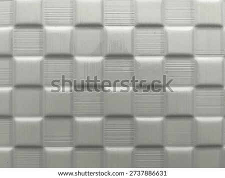 Texture of minimalist background featuring a pattern of square tiles. Arranged in a uniform grid, with subtle embossed texture, alternating between plain squares and squares with fine horizontal lines. Perfect for backgrounds, textures, and designs requiring a simple yet refined visual element.