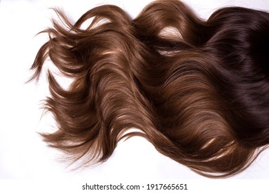 A Texture Of Natural Looking Synthetic Dark Brown Copper Shiny Wavy Curly Hair Isolated On The White Background