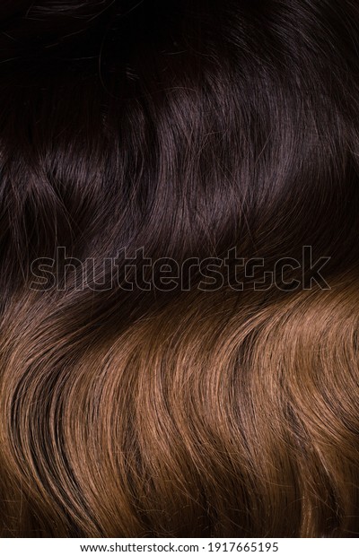 A texture of natural looking synthetic dark\
brown and walnut wavy curly\
hair