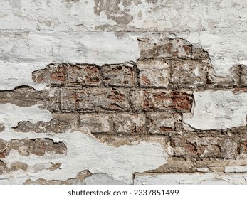 Texture of old brick wall with collapsed plaster. Background of shabby building surface. Destroyed stone wall with fallen plaster. Weathered surface. Copy space. Selective focus.