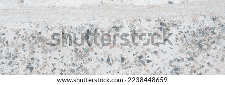 The texture of the old concrete wall. A rough gray concrete surface with many small pebbles. Great for background and design. Close-up.