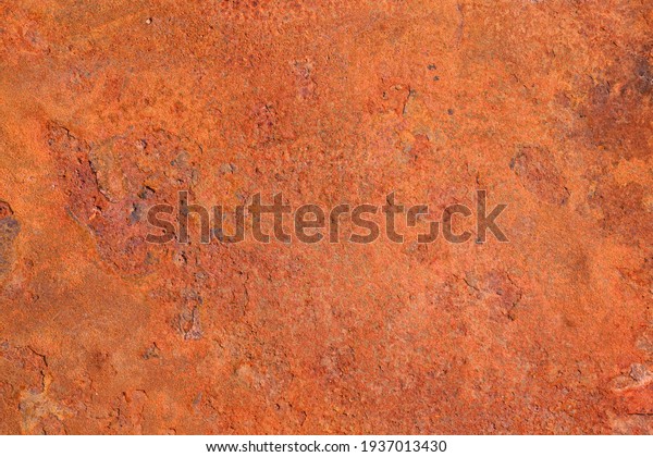 The texture\
of an old metal surface coated with a layered orange rust. The\
corrosion of metals under the influence of natural conditions\
resembles the surface of the red planet\
Mars.